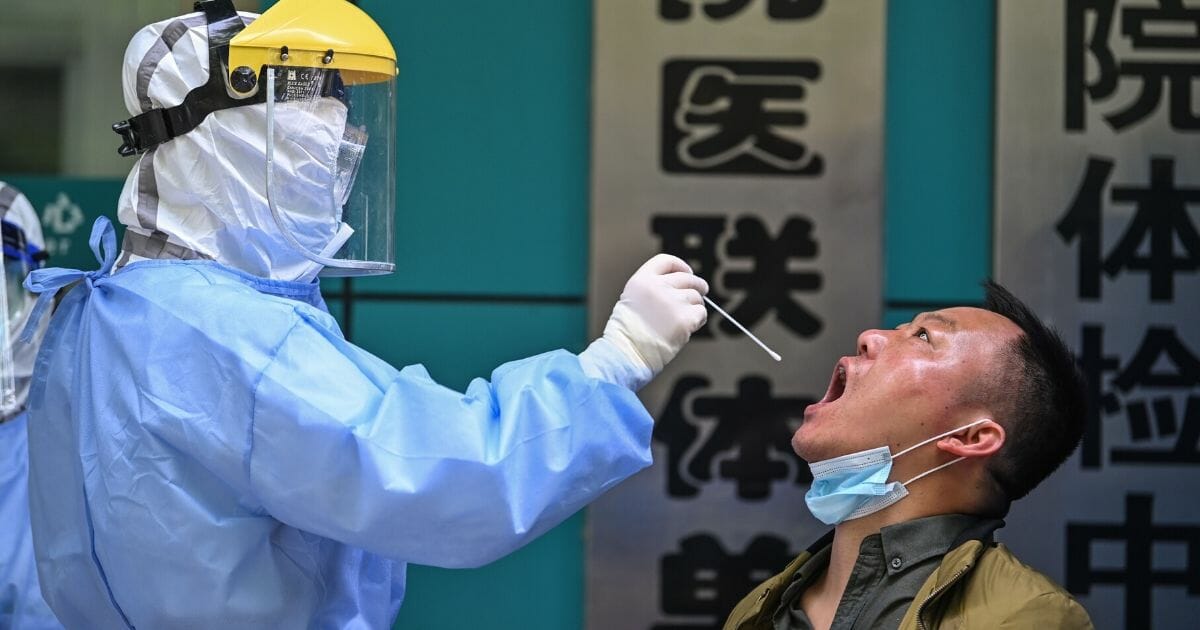 A medical worker takes a swab sample from a man being tested for the COVID-19 novel coronavirus in Wuhan in China's central Hubei province on April 16, 2020.