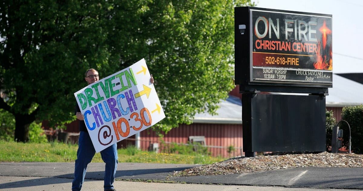 A worshiper holds a sign to alert drivers to a drive-in service