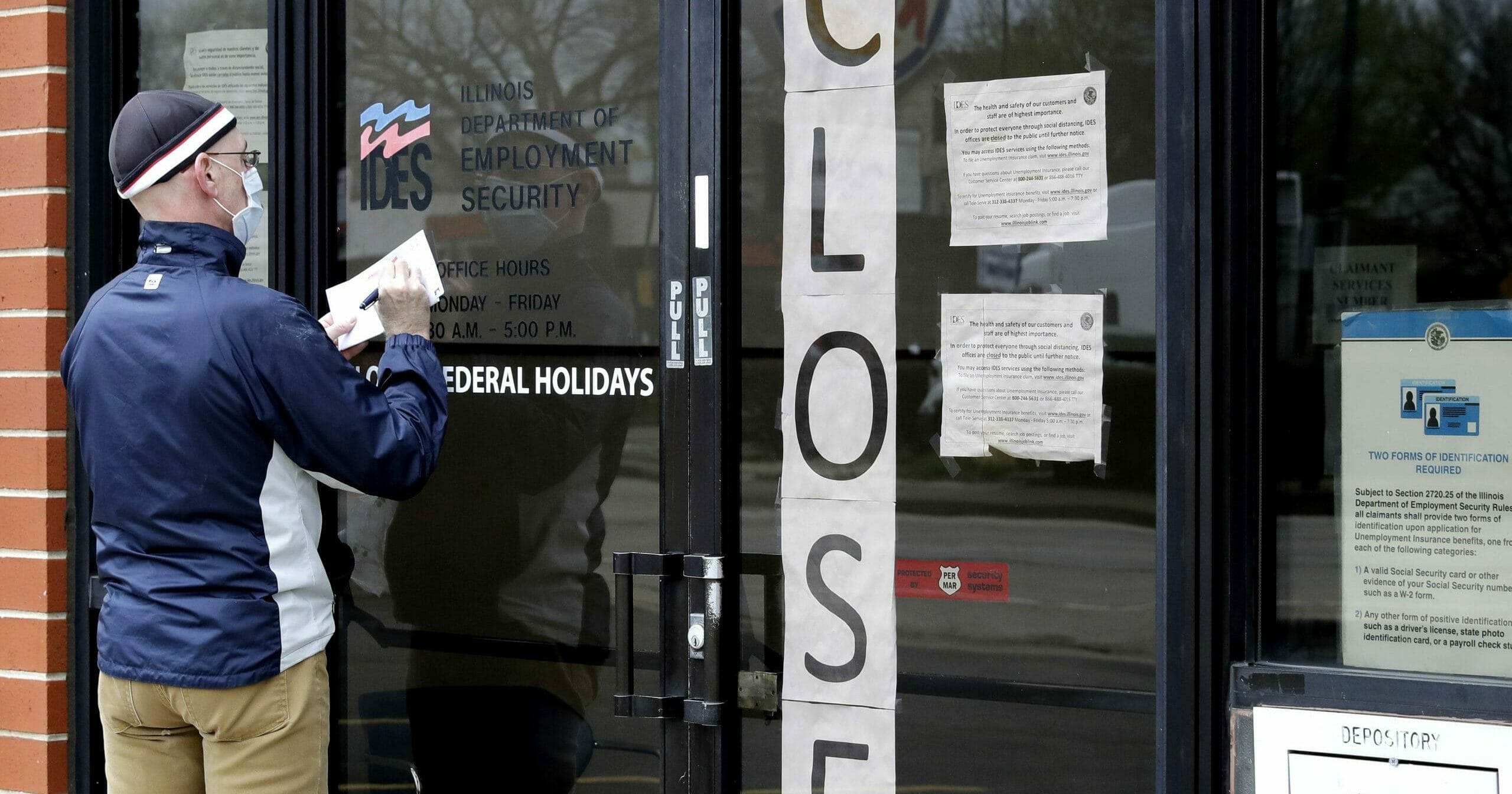 A man writes information in front of the Illinois Department of Employment Security in Chicago on April 30, 2020.