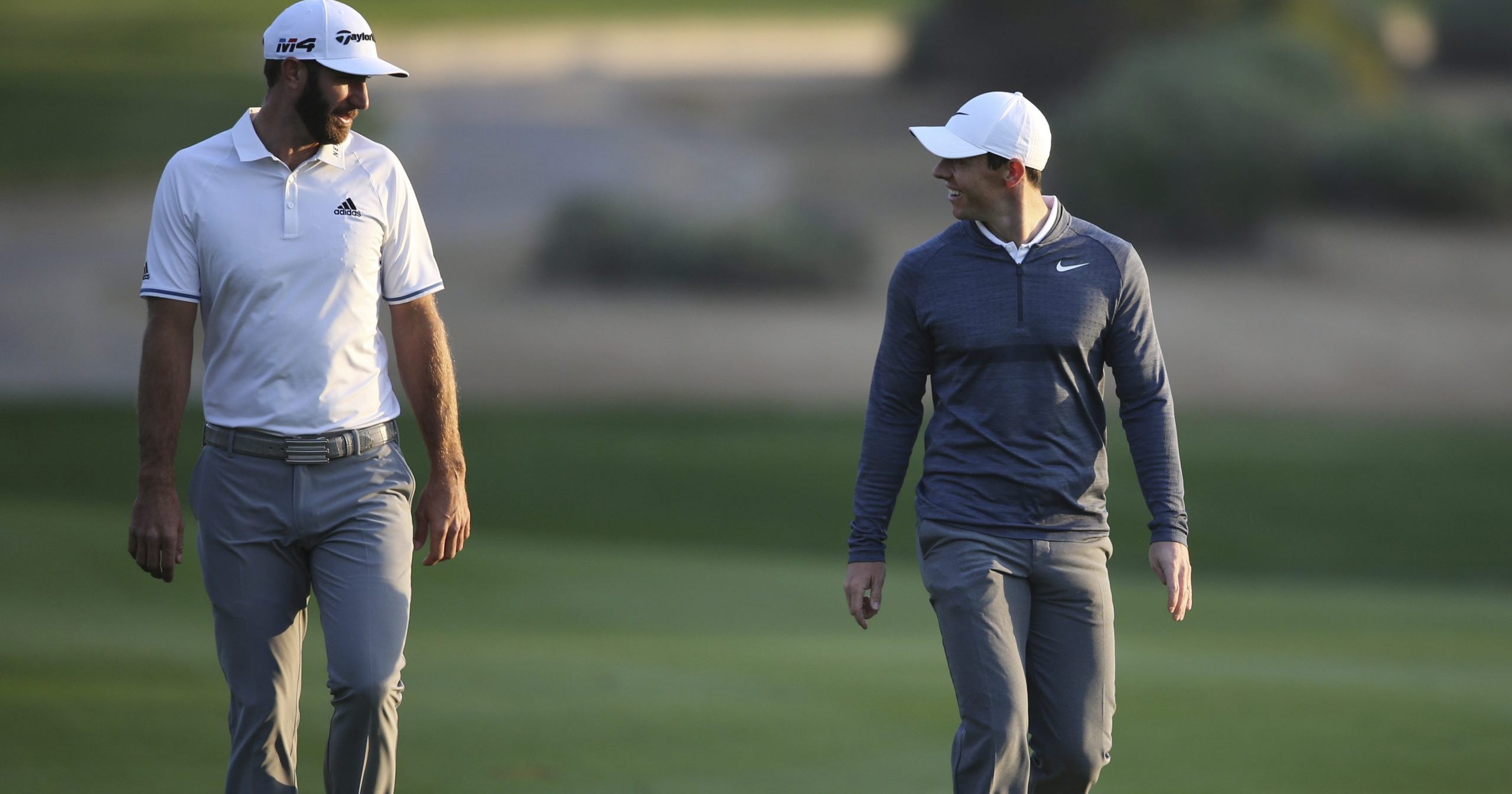 In this Jan. 18, 2018, file photo, Dustin Johnson of the United States, left, and Rory McIlroy of Northern Ireland talk on the 10th fairway during the first round of the Abu Dhabi Championship golf tournament in Abu Dhabi, United Arab Emirates.