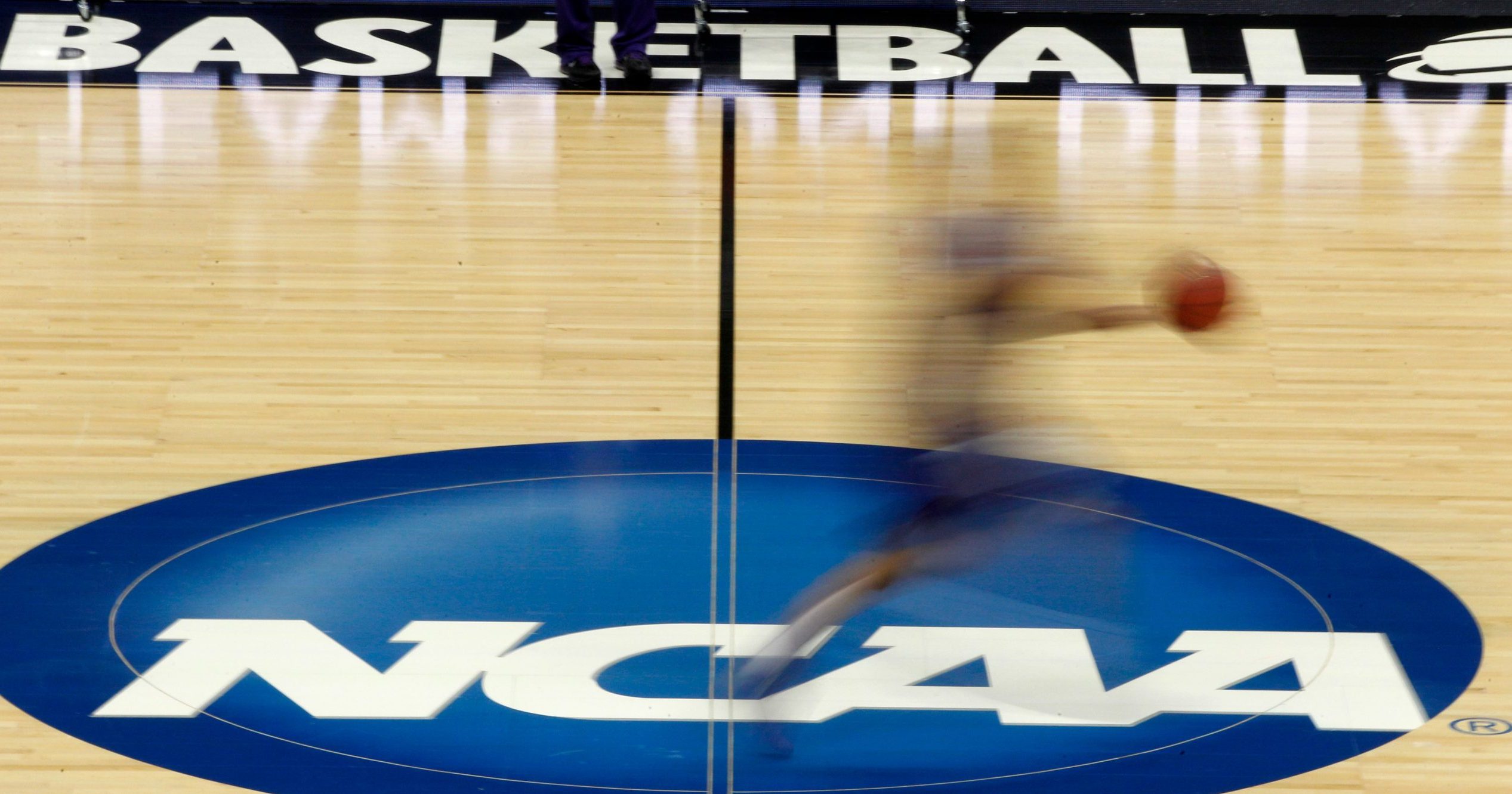 A player runs across the NCAA logo during practice in Pittsburgh before an NCAA tournament college basketball game.