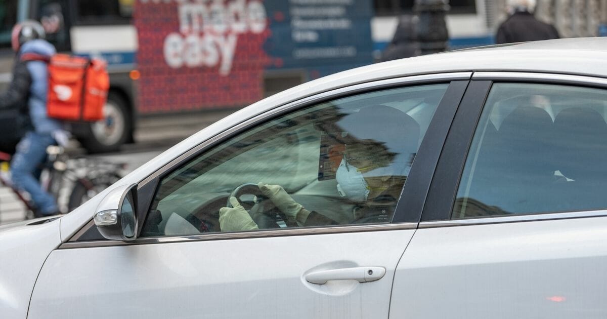 A woman wearing a protective mask and gloves drives in New York City on April 16, 2020.
