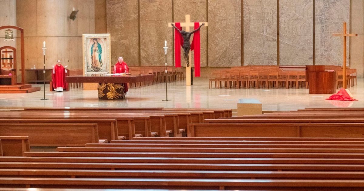 Archbishop Jose Gomez, right, and Father Brian Nunez celebrate Good Friday liturgy in a nearly empty Cathedral of Our Lady of the Angels on April 10, 2020, in Los Angeles.