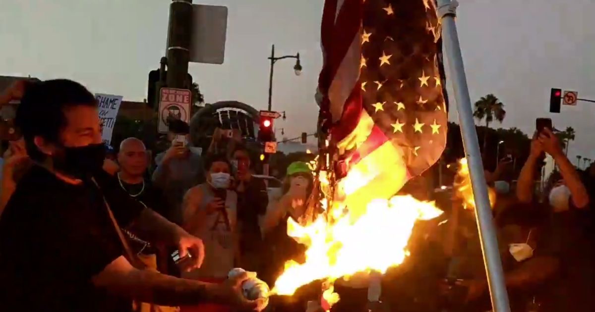 Crowd gathers as flag is burned