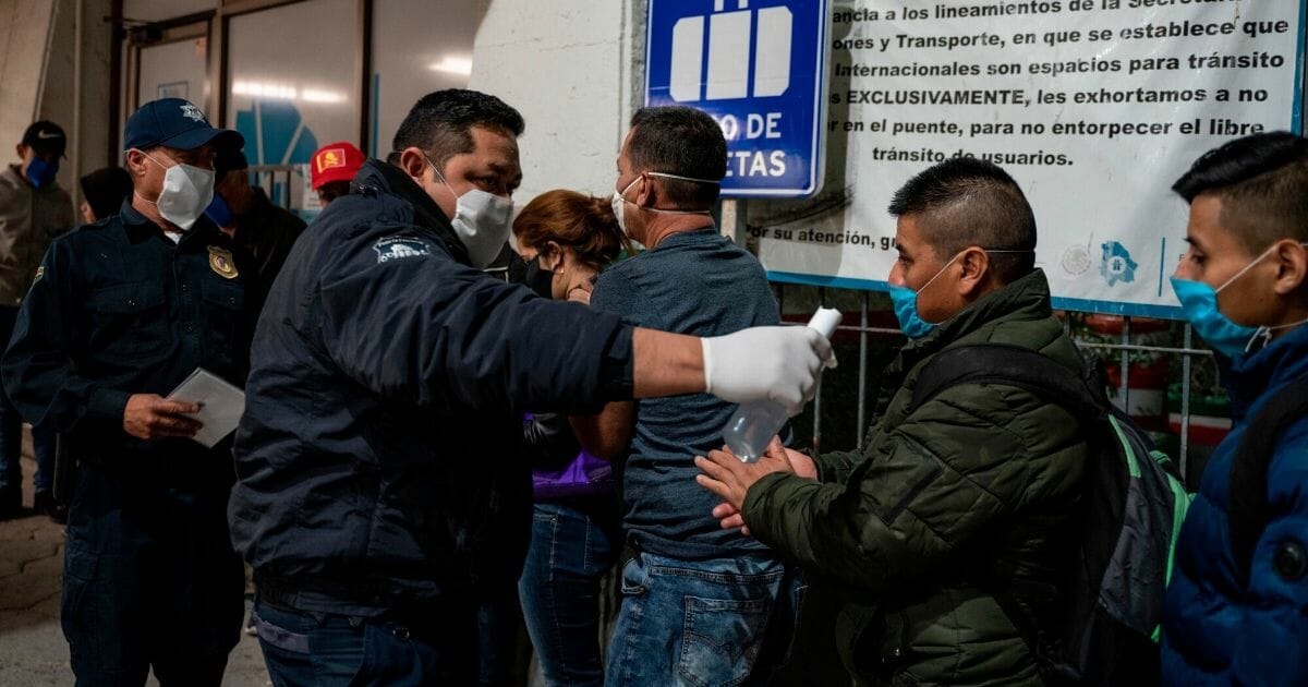 A police officer gives out hand sanitizer to migrants at the Paso del Norte International Bridge in Ciudad Juarez, Mexico, on April 6, 2020.