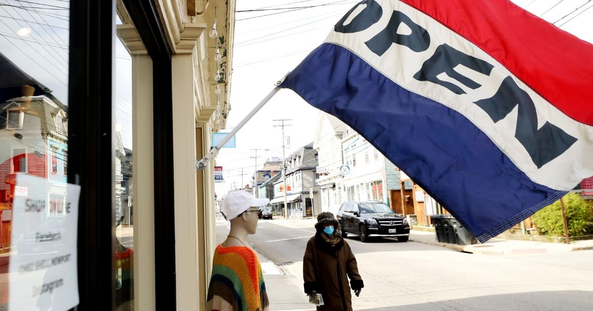 A pedestrian walks down Thames Street past open boutiques on May 9, 2020, in Newport, Rhode Island.