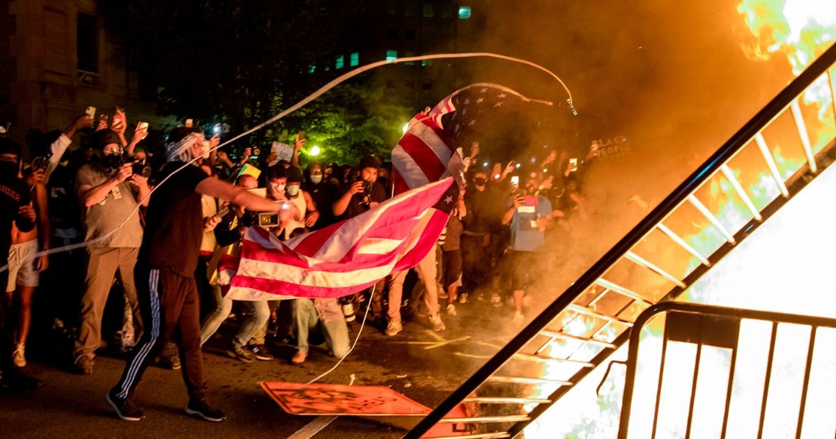 Rioters throw an American flag into a fire during a demonstration outside the White House on May 31, 2020.
