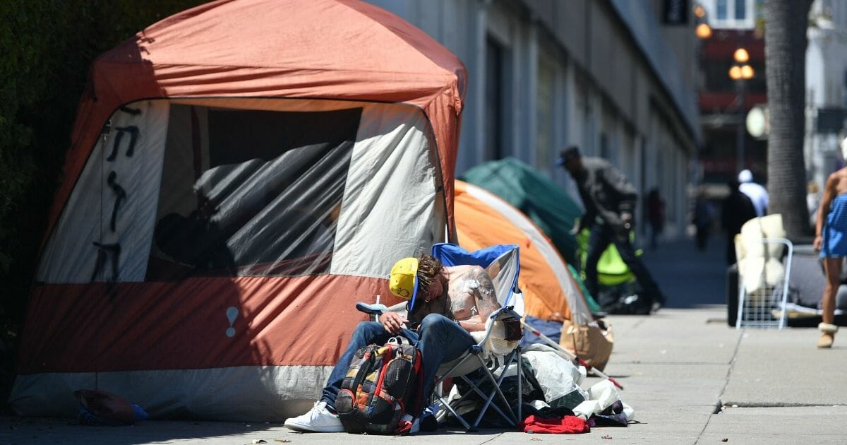 A homeless man sleeps in front of his tent along Van Ness Avenue in downtown San Francisco, California, on June, 27, 2016.