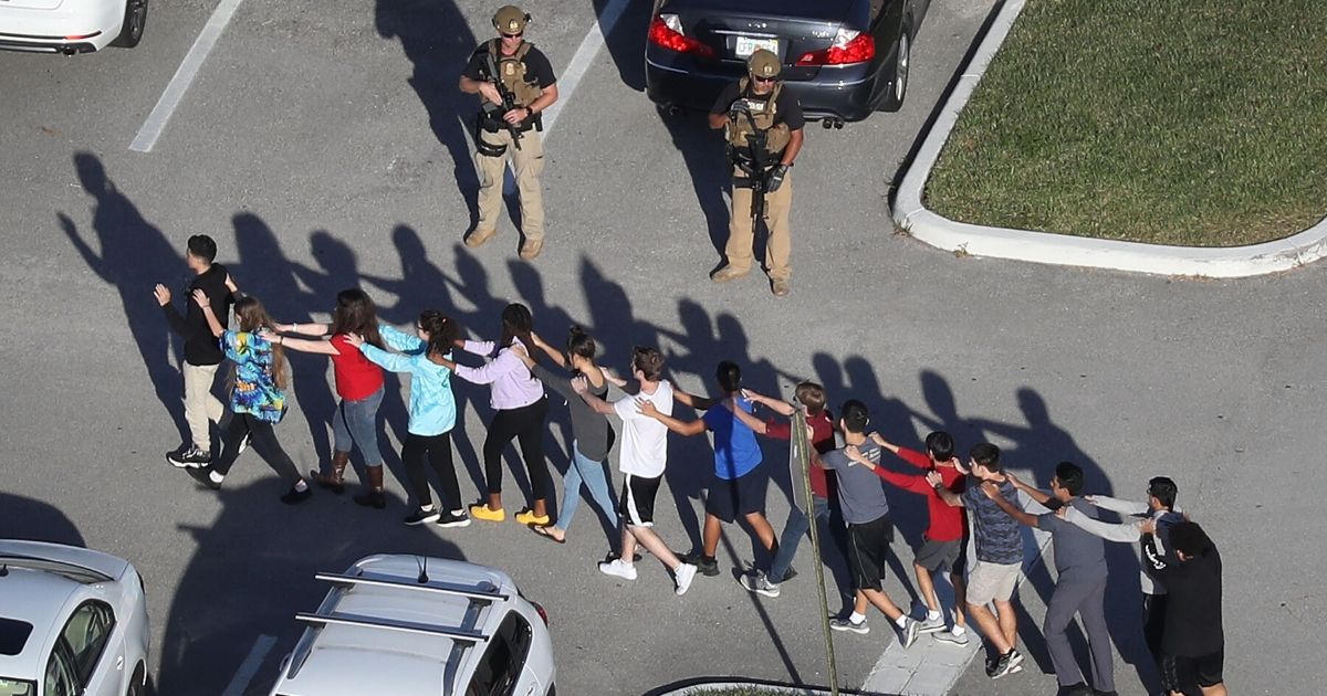 People are brought out of Marjory Stoneman Douglas High School after a shooting at the school on Feb. 14, 2018, in Parkland, Florida.