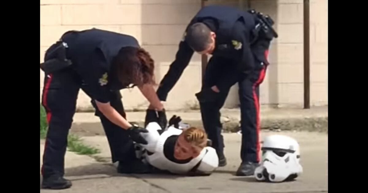 Police officers handcuff a 19-year-old woman who was holding a plastic gun as part of a "Star Wars" Stormtrooper character costume outside the Coco Vanilla Galactic Cantina in Lethbridge, Alberta.