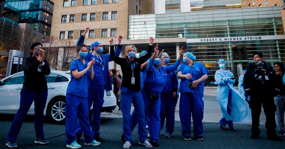 Health care workers cheer as first responders parade down hospital row in Toronto on April 19, 2020, amid the novel coronavirus pandemic.