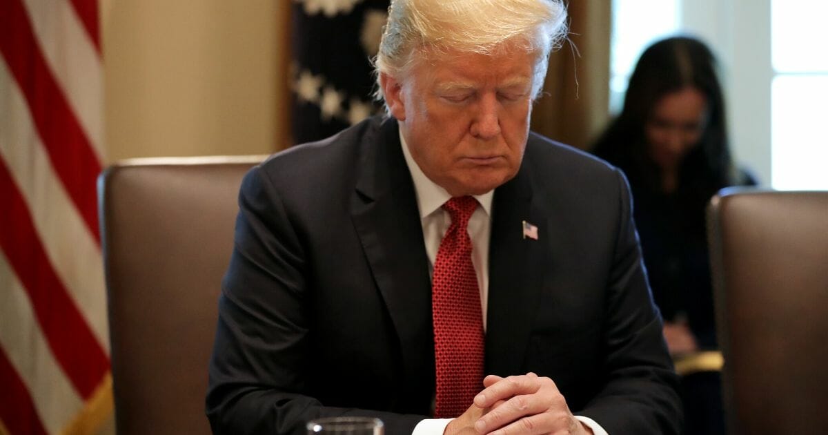 President Donald Trump closes his eyes during a prayer before a meeting of his Cabinet at the White House on Oct. 17, 2018.