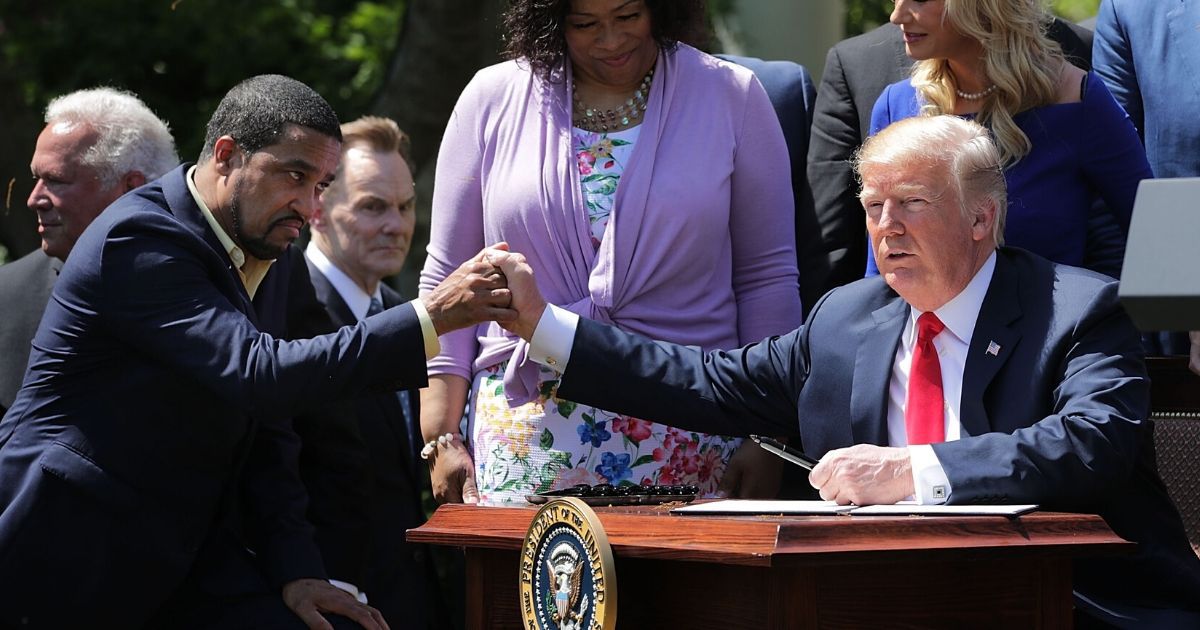 President Donald Trump shakes hands with Pastor Darrell Scott, co-founder of the New Sirit Revival Center, before Trump signs an executive order during an event in the Rose Garden to mark the National Day of Prayer at the White House May 3, 2018, in Washington, D.C.