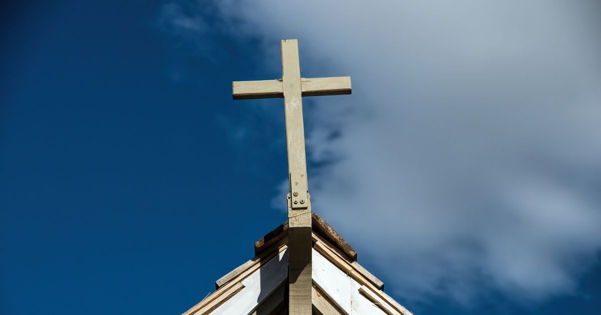 A cross above a church with the sky in the background.