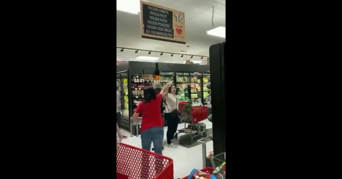 A crowd of people shout at an unmasked woman in a Staten Island grocery store in New York City.