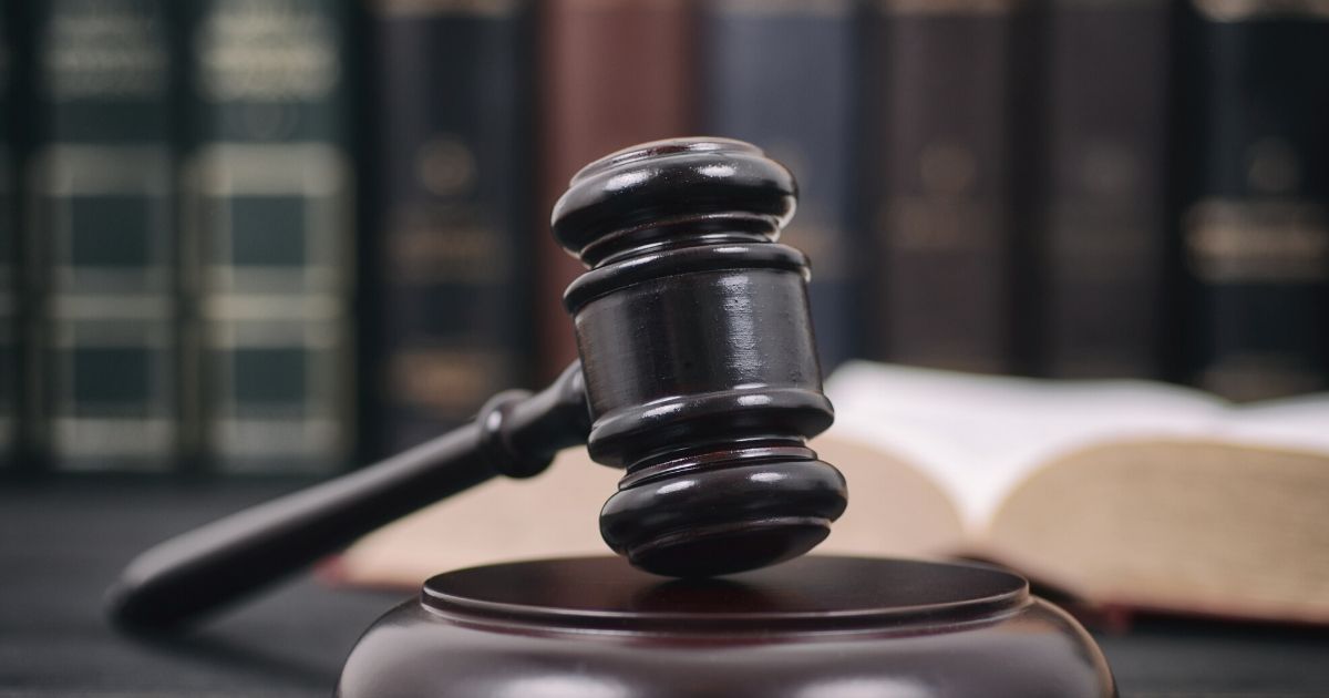 Stock image of a gavel and a shelf of legal texts.