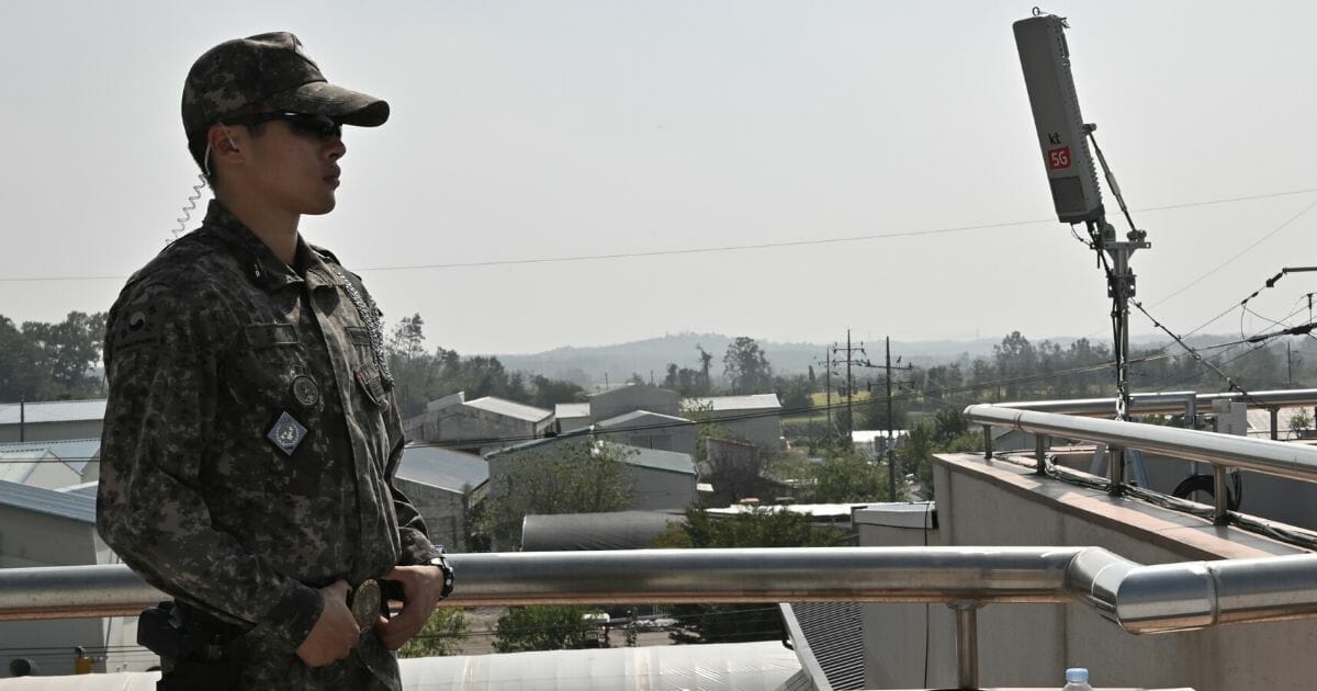 A South Korean soldier stands guard next to an antenna for the 5G mobile network service on the rooftop of a building during a media tour to the Taesungdong freedom village in the Demilitarized Zone dividing the two Koreas in Paju on Sept. 30, 2019.