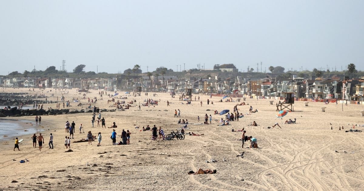 People gather on the beach north of Newport Pier on May 3, 2020, in Newport Beach, California.