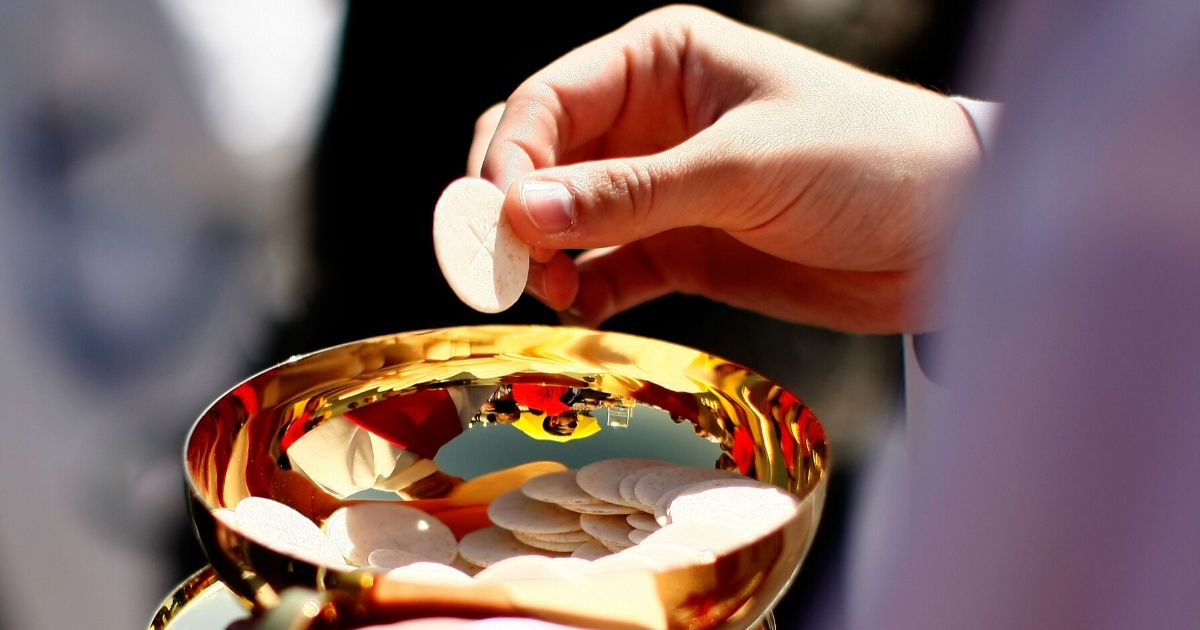 A priest holds a Holy Communion wafer as Pope Benedict XVI celebrates Mass at Nationals Park in Washington on April 17, 2008.