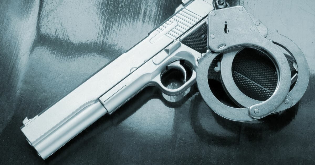 Stock image of a handgun and handcuffs on a table.