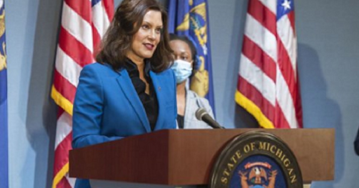 Michigan Gov. Gretchen Whitmer speaks behind a podium with the state of Michigan seal on its front.