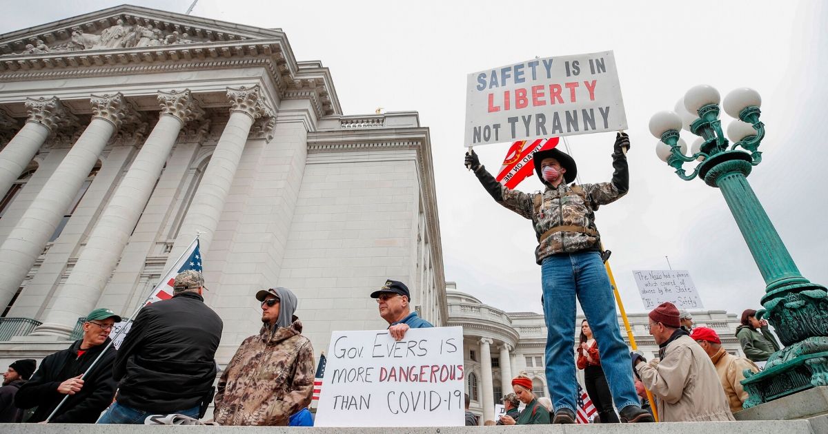 People hold signs during a protest against Wisconsin's coronavirus shutdown in front of the state Capitol in Madison on April 24, 2020.