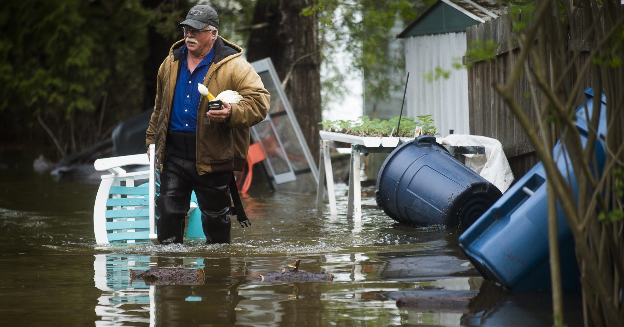 Mark Musselman brings a chair to the front of his house from the back yard, wading through floodwater on May 19, 2020, in Edenville, Michigan.