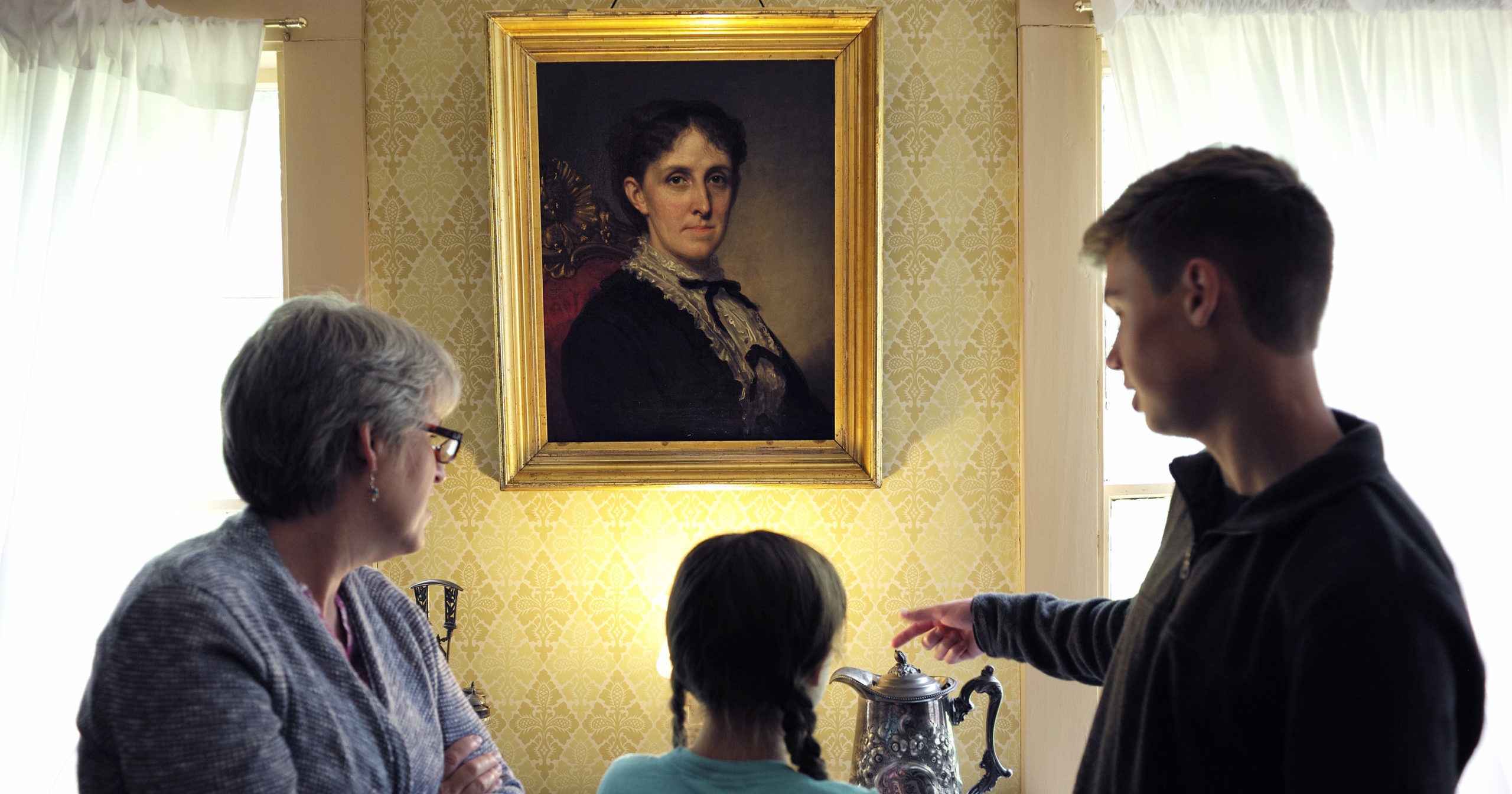 In this May 17, 2018, file photo, museum visitors stand near a portrait of author Louisa May Alcott at Orchard House in Concord, Massachusetts. The current issue of The Strand Magazine will give readers the chance to discover an obscure and unfinished work of fiction by Alcott, "Aunt Nellie's Diary," and to provide a conclusion themselves.