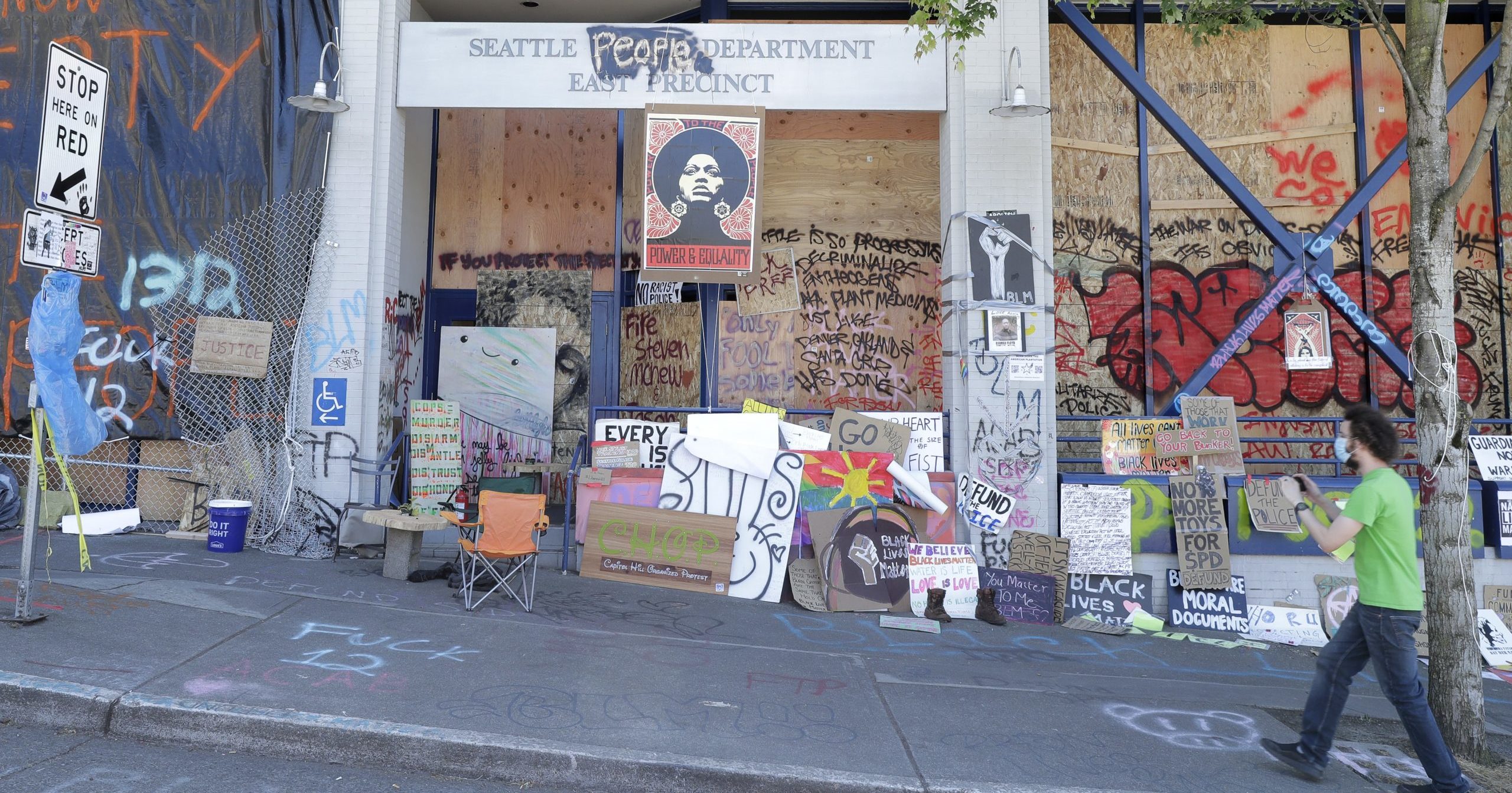 A person takes a photo of the Seattle Police East Precinct building on June 22, 2020, inside what has been named the Capitol Hill Occupied Protest zone in Seattle. For the second time in less than 48 hours, there was a shooting near the "CHOP" area that has been occupied by protesters after police pulled back from several blocks of the city's Capitol Hill neighborhood.