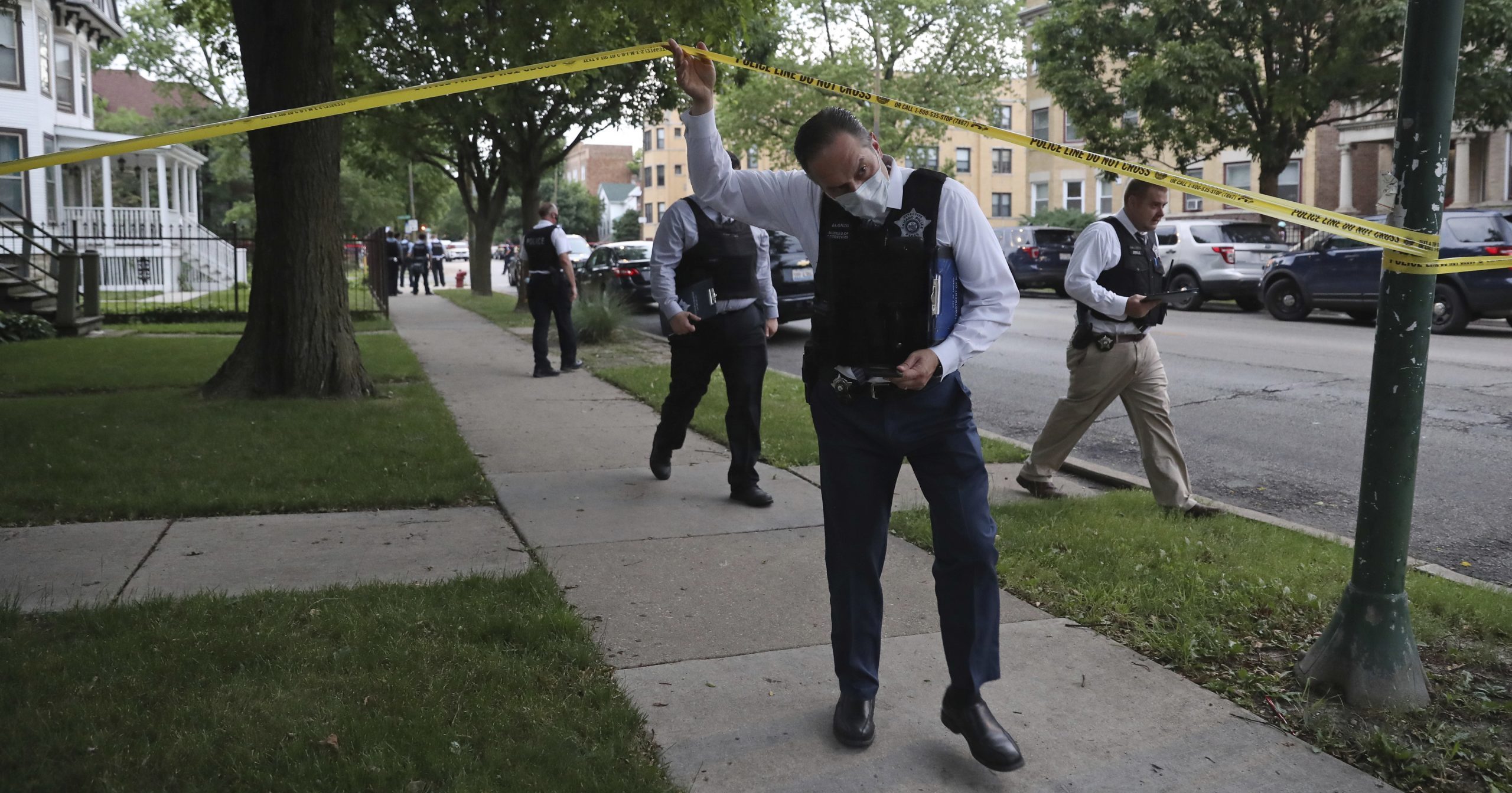 Police detectives canvas the area where a 3-year-old boy was fatally shot while riding in an SUV with his father on June 20, 2020, in Chicago. More than 100 people were shot in a wave of gunfire in Chicago over the Father’s Day weekend that produced the city’s highest number of shooting victims in a single weekend this year.