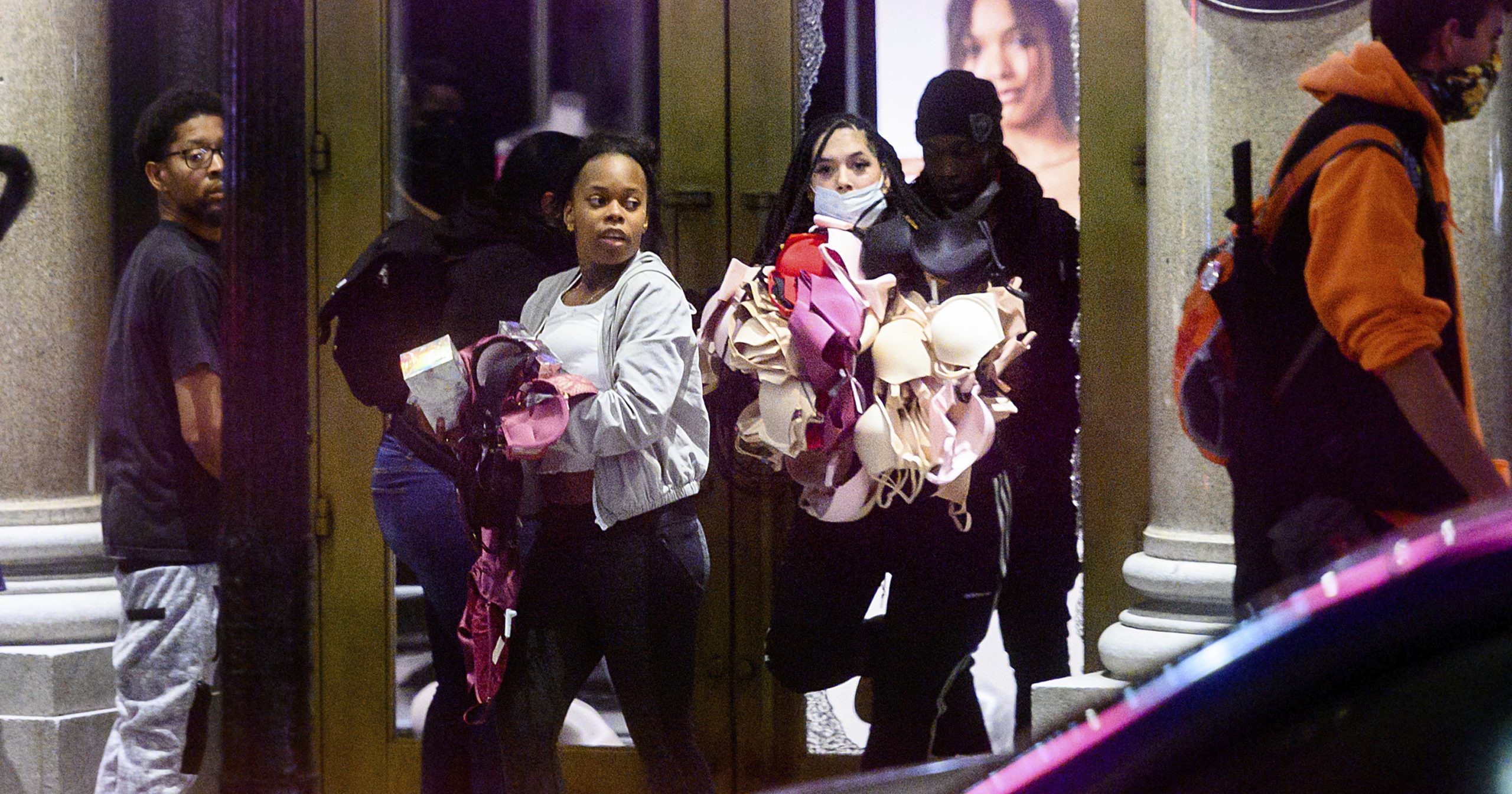 In this May 30, 2020, file photo, women carry merchandise from a Union Square Victoria's Secret store in San Francisco. Police say many of the smash-and-grab thefts have been carried out by caravans of well-coordinated criminals and have coincided with or followed protests over the death of George Floyd.