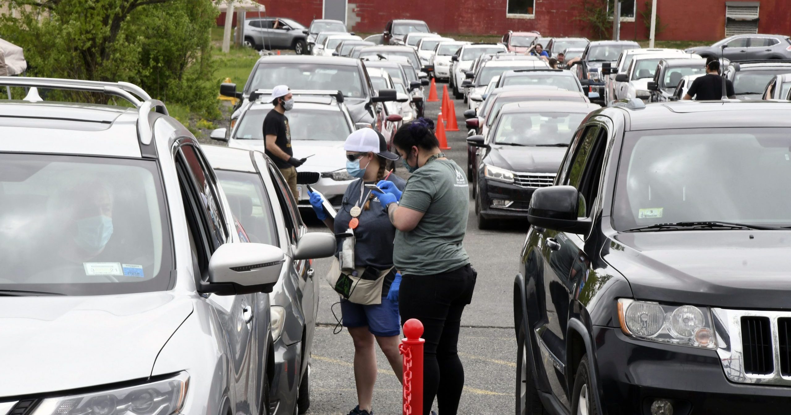 Amanda Toma and Ashley Brodeur work with customers in the parking lot of cannabis purveyor Berkshire Roots in Pittsfield, Massachusetts, on May 25, 2020.