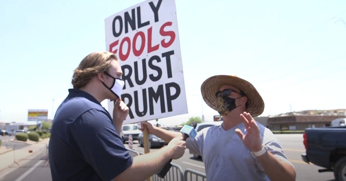 Michael Austin of The Western Journal talks to an anti-Trump poster during a rally in Phoenix.