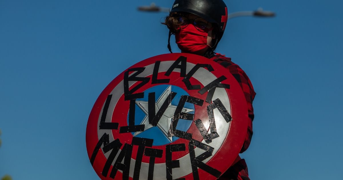 A protester holds a Captain America Black Lives Matter shield while four symbolic funeral processions converge in downtown at the intersection of 1st St and Broadway on June 8, 2020, in Los Angeles.