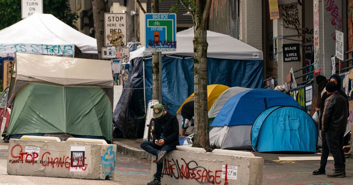 A person sits on a concrete barrier in the Seattle area known as the "Capitol Hill Organized Protest" on June 28, 2020.