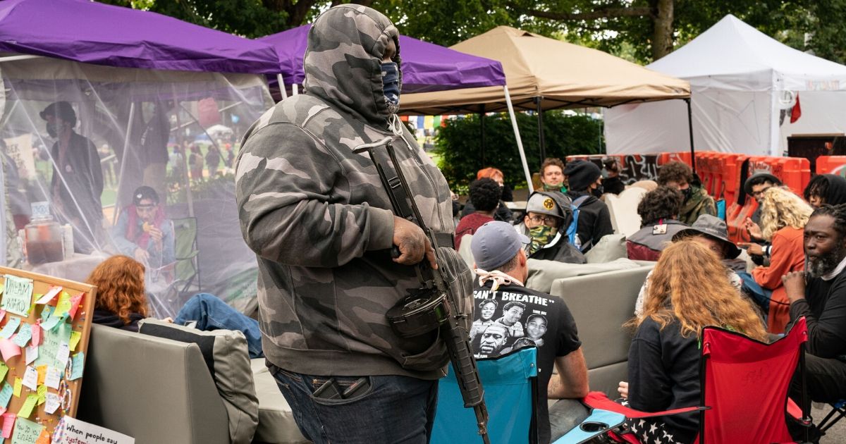 A man with a rifle stands in the "Conversation Cafe" in the so-called Capitol Hill Organized Protest zone of Seattle on June 15, 2020.