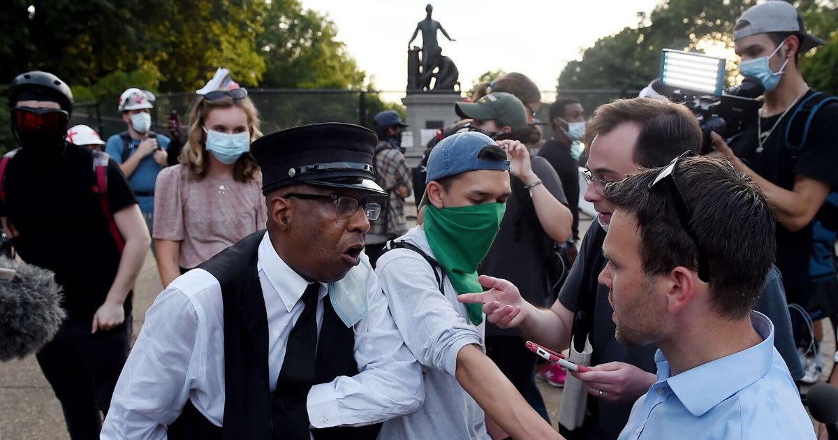 Tour guide Don Folden, left, and conservative activist Jack Posobiec, right, argue with protesters calling for the removal of the Emancipation Memorial at Lincoln Park in Washington, D.C., on June 26, 2020.