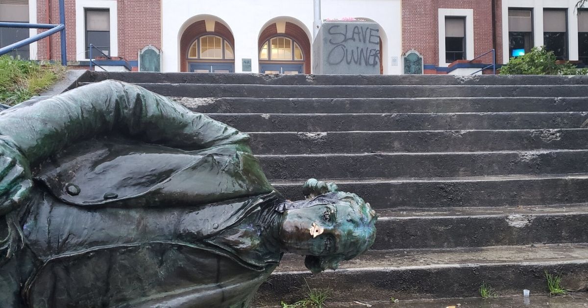 A statue of Founding Father Thomas Jefferson lies at the bottom of the steps in front of Jefferson High School in Portland, Oregon.