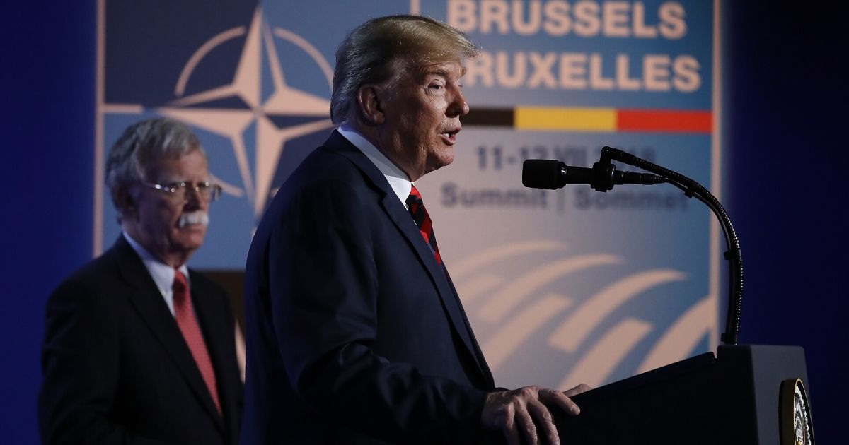 President Donald Trump, flanked by then-National Security Advisor John Bolton, speaks to the media at a news conference on the second day of the 2018 NATO Summit on July 12, 2018, in Brussels, Belgium.