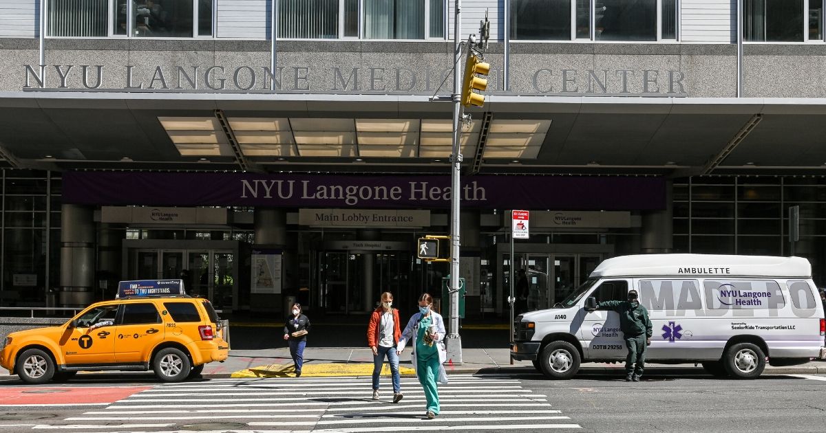 People wearing face masks cross the street in front of NYU Langone Medical Center in New York City on April 28, 2020.