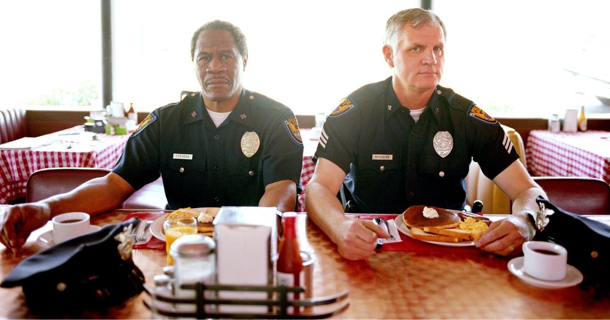 Two police officers are seen eating breakfast at a diner.