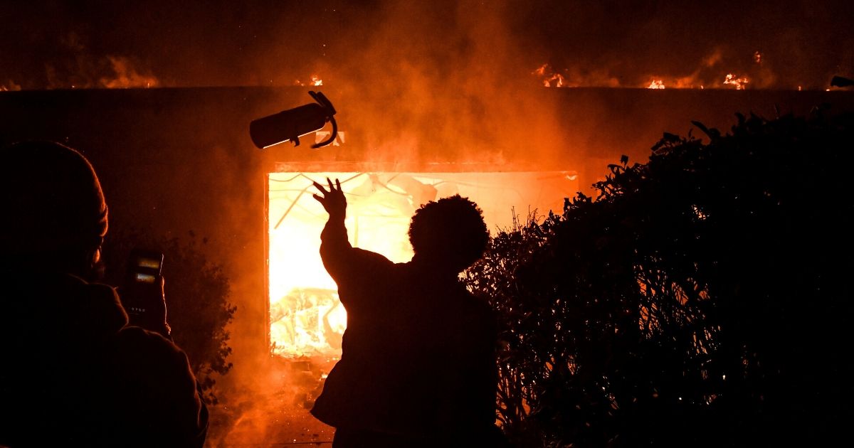 A protester throws a fire extinguisher in a burning building during a demonstration in Minneapolis, Minnesota, on May 29, 2020.