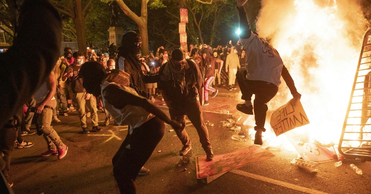 Rioters jump on a street sign near a burning barricade during a demonstration against the death of George Floyd near the White House in Washington on May 31, 2020.