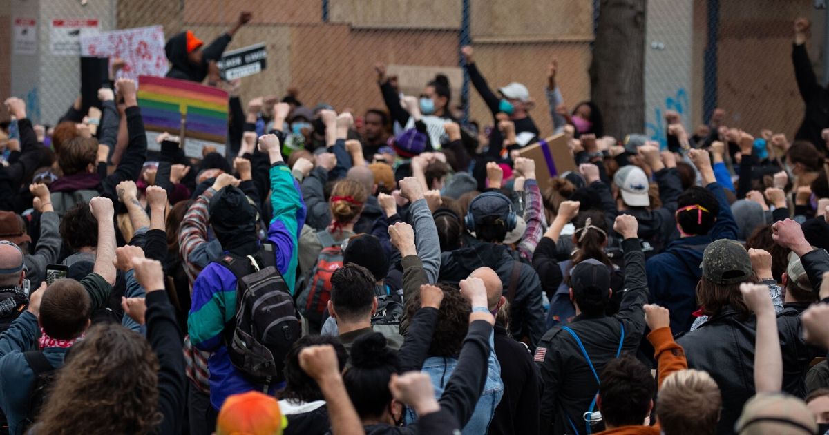 Demonstrators raise their fists outside of the Seattle Police Department's East Precinct, which was abandoned and boarded up, on June 8, 2020.