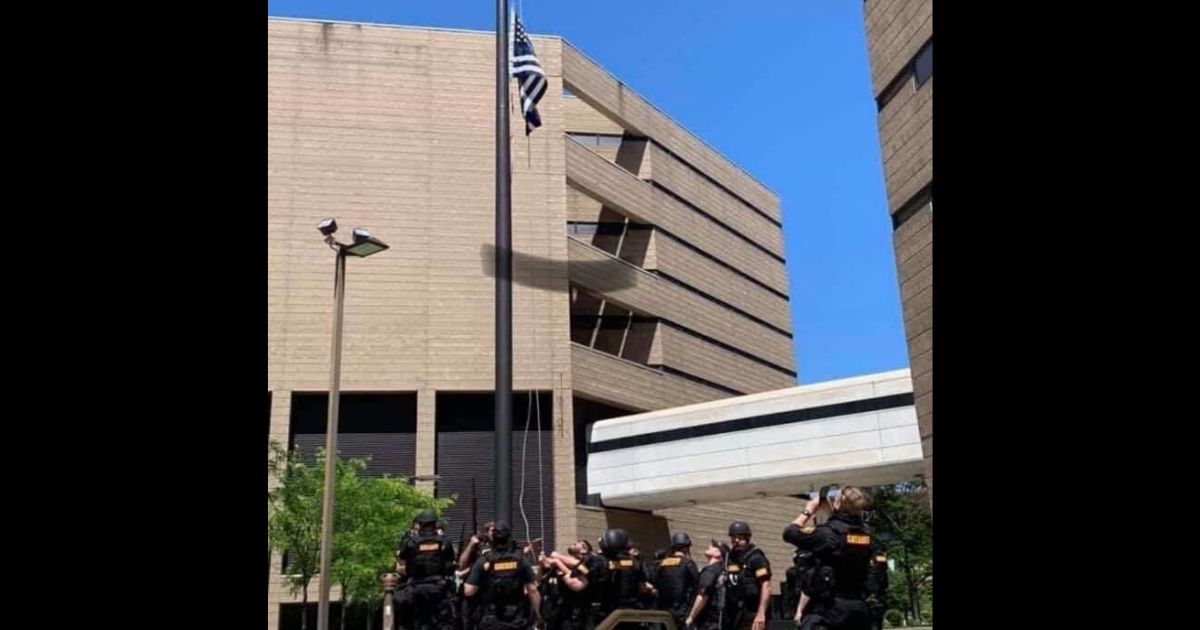 A "thin blue line" flag is raised outside the Hamilton County Justice Center in Cincinnati.