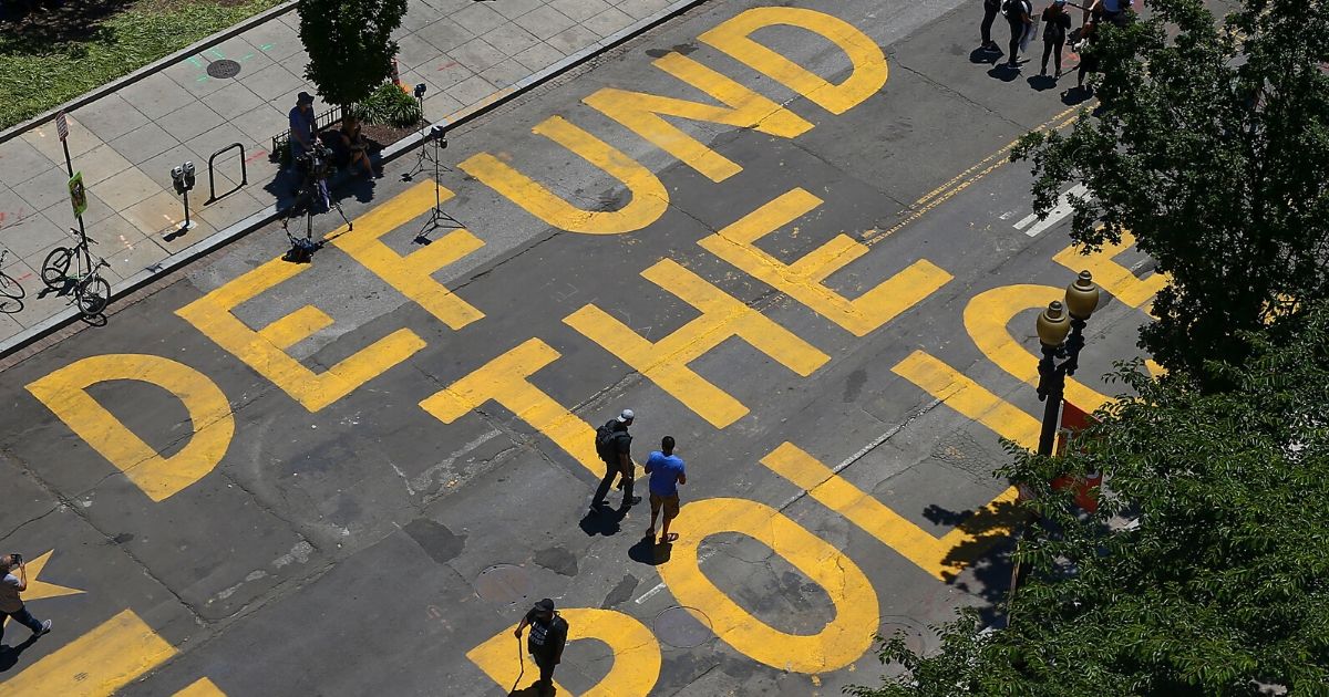 People walk down 16th Street after “Defund The Police” was painted on the street near the White House on June 8, 2020, in Washington, D.C.
