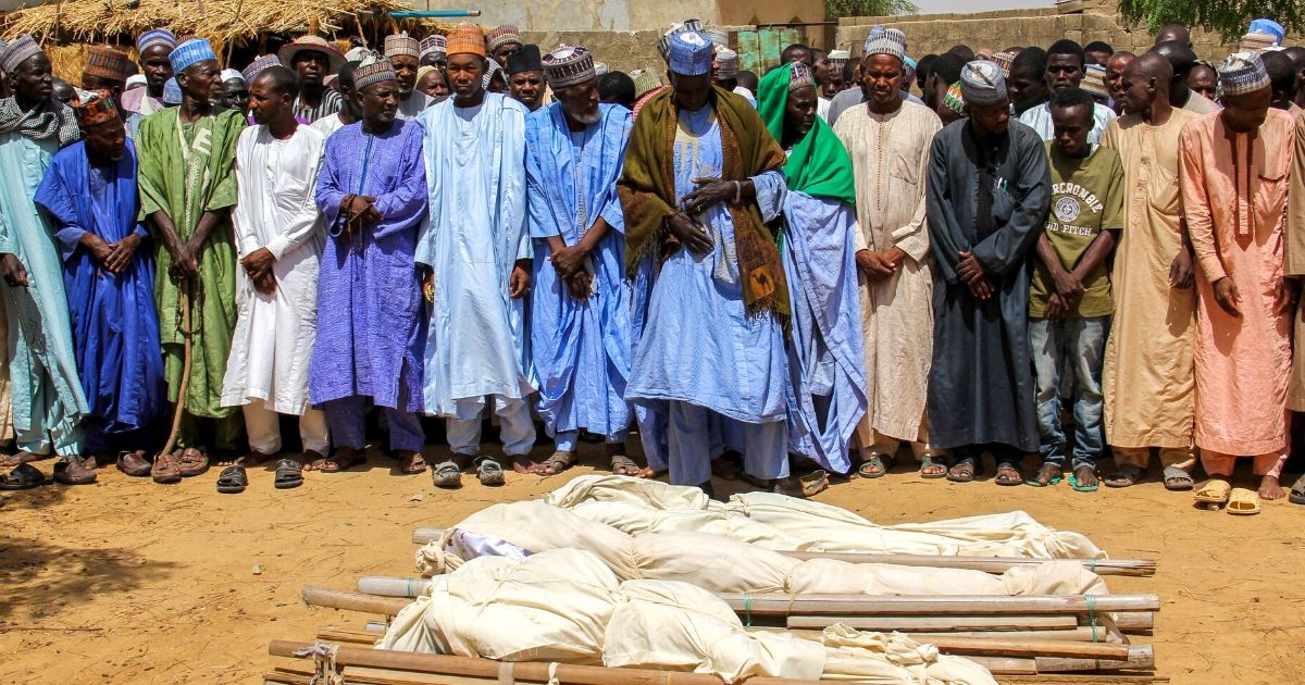 Men pray next to coffins during a burial ceremony after two people were killed by Boko Haram terrorists near Maiduguri, Nigeria, on July 26, 2019.