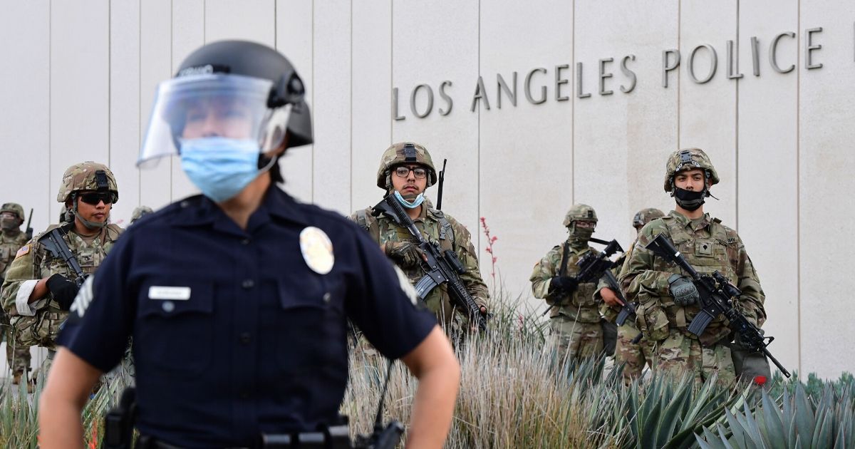 A Los Angeles police officer is suported by members of the California National Guard during rioting in the city on June 1.