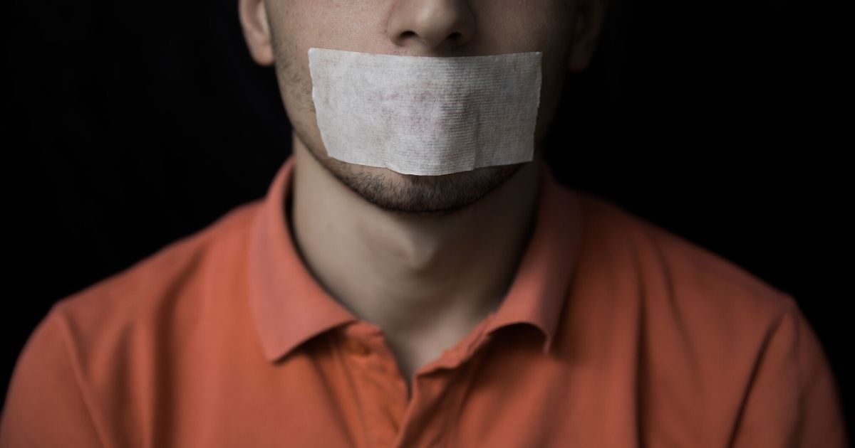 Stock image of a man with adhesive tape on his mouth.