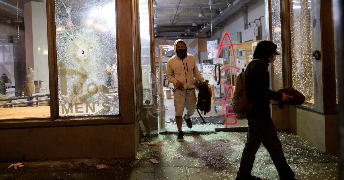 Looters emerge from an Urban Outfitters store with stolen property during a May 30 riot in Seattle.